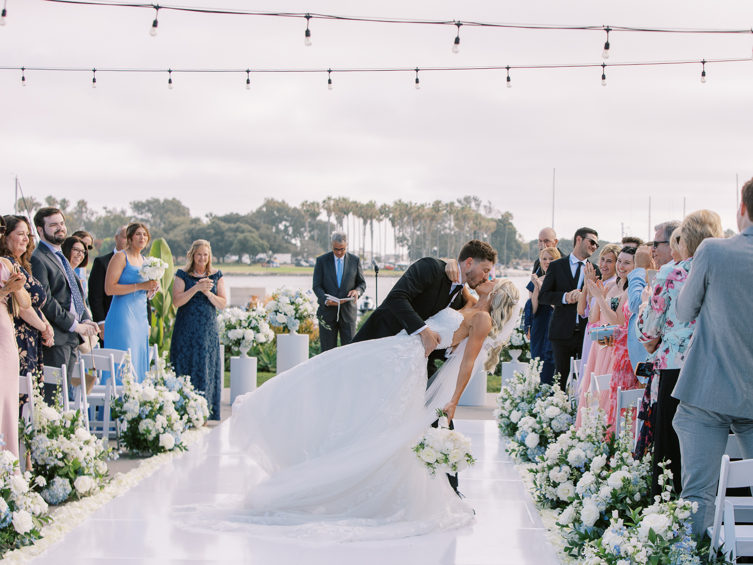 The grooms dips the bride for a kiss in the center of their ceremony aisle at Paradise Point