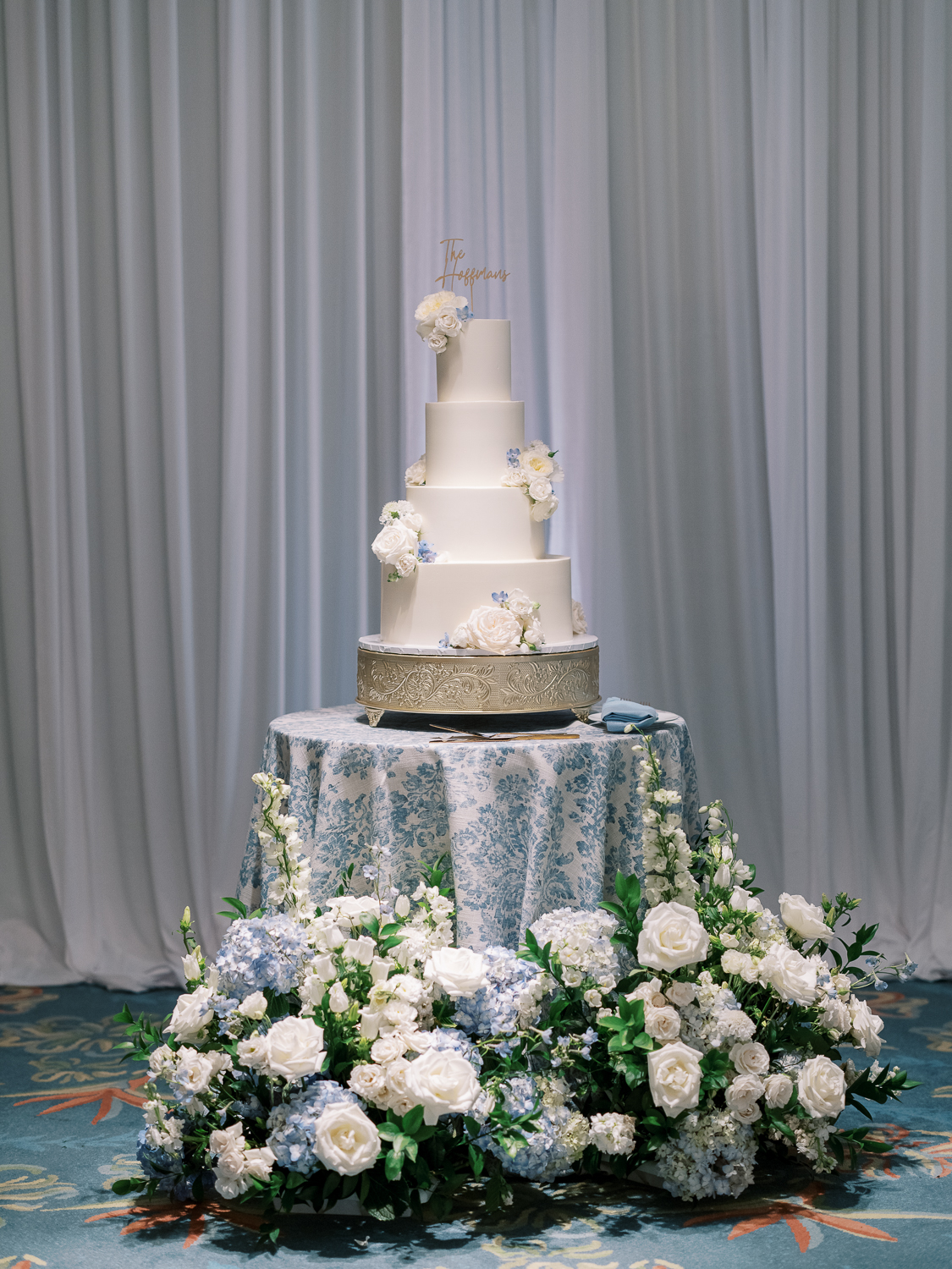 A towering tiered cake by Fab Cakes in the white and blue wedding color palette.