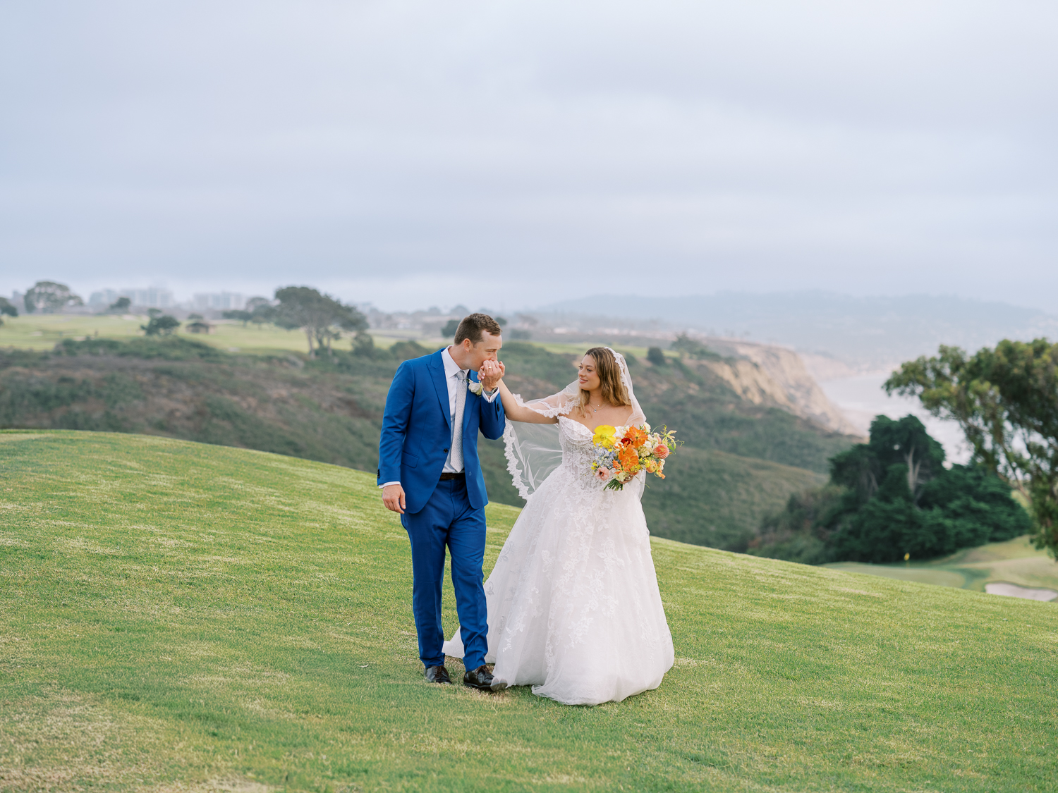 The groom kisses the bride's hand at The Lodge at Torrey Pines golf course