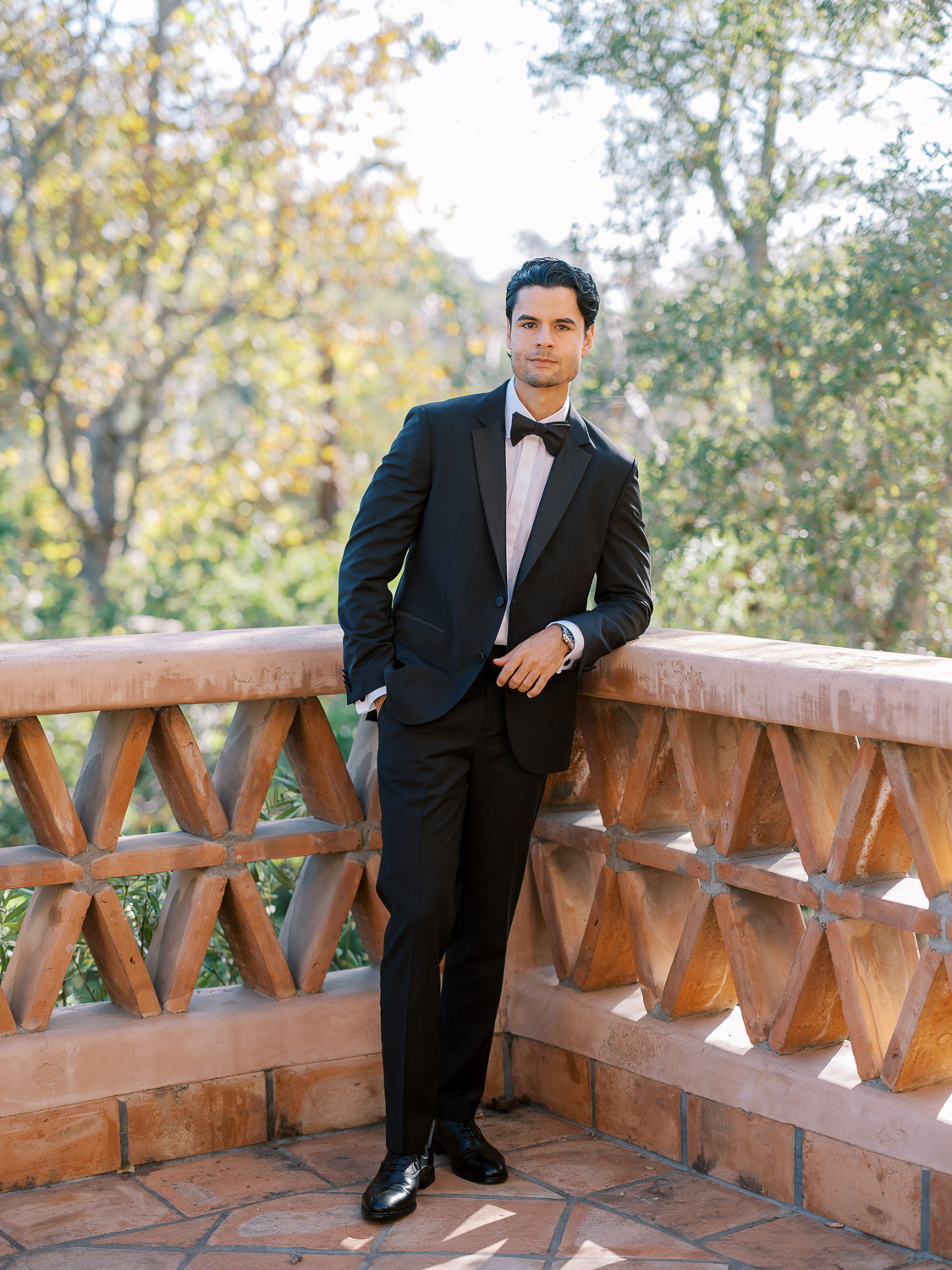 groom leaning on terrace rail outside rancho valencia 