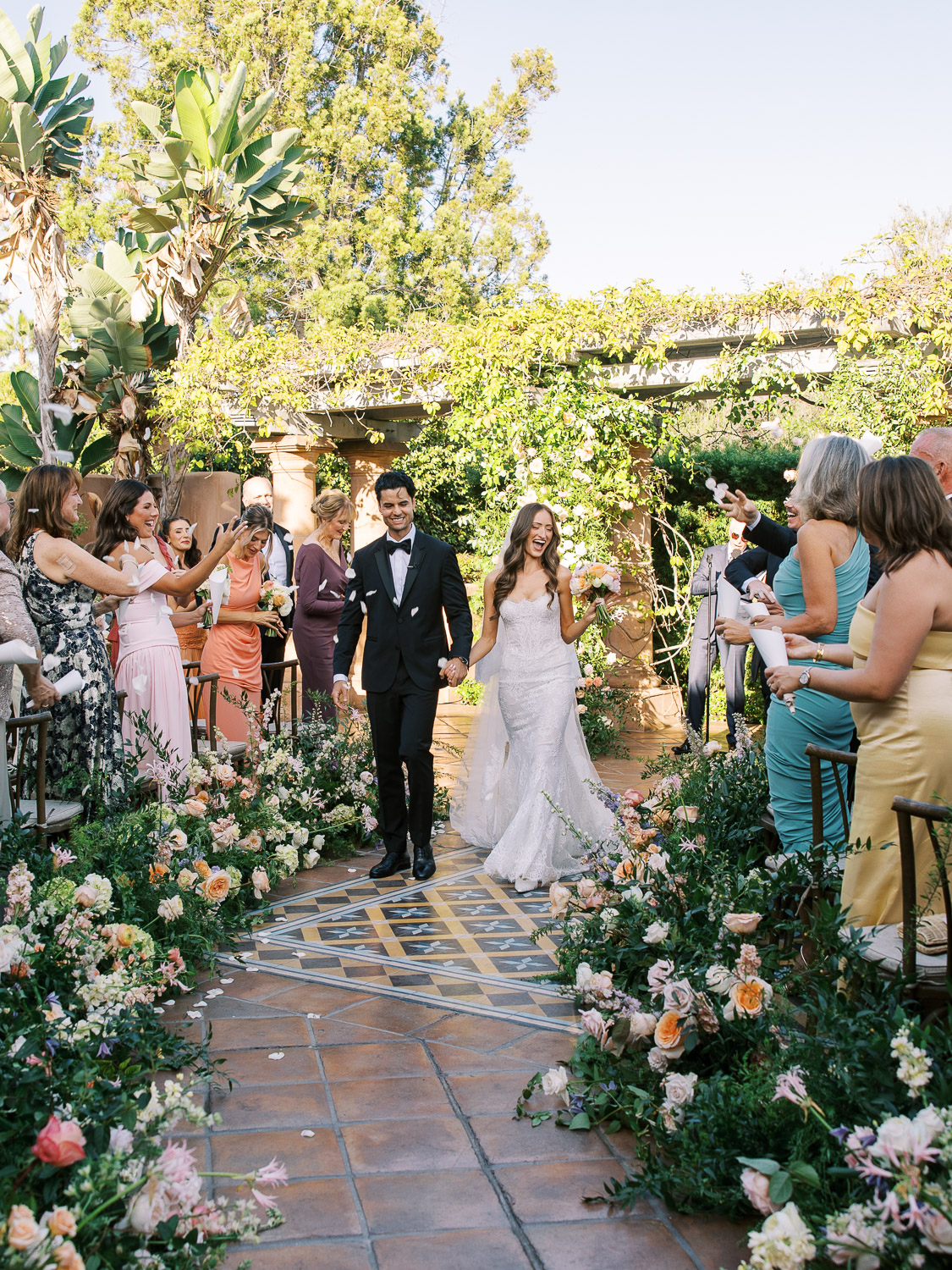 bride and groom walk down the colorful aisle in celebration on sunrise patio rancho valencia